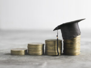 College cost depicted with coins and a small graduation cap