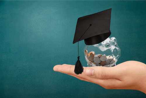 hand holding money with college graduation cap