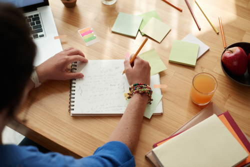 Female student writing down essay ideas in her notebook
